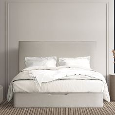 a bed with white linens and pillows in a neutral bedroom setting on carpeted flooring