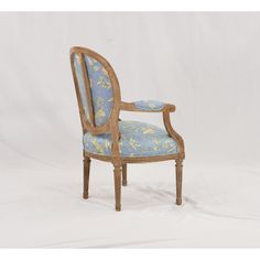 an antique chair with blue and yellow floral upholstered fabric on the armrests