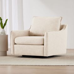 a white chair sitting on top of a wooden floor next to a potted plant