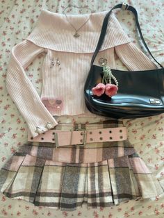 a skirt, sweater and handbag are laid out on a bed