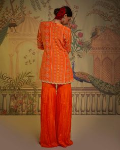 Editor's Note The tangerine patola tunic, garara, and dupatta ensemble is a stunning combination of traditional and contemporary styles. The tunic features intricate patola patterns in vibrant tangerine hues, adding a touch of elegance to the outfit. Paired with the matching garara pants, which offer a comfortable and stylish fit, and the beautifully crafted dupatta, this ensemble exudes grace and charm. Color: Orange Fabric: Tunic: crepe silk, gharara: georgette crepe, dupatta: net Components: Silk Gharara, Churidar Sleeves, Patola Print, Blouse Yoke, Cape Tops, Drape Saree, Embroidered Dupatta, Orange Fabric, Traditional Fashion