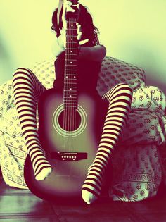 a woman in striped stockings holding a guitar