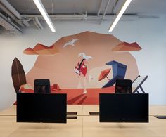 two black speakers sitting on top of a wooden table in front of a wall mural