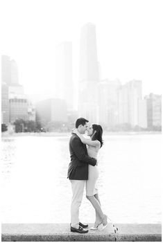 a man and woman standing next to each other in front of a body of water