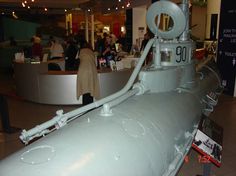 a large metal object on display in a building with people standing around and looking at it