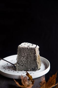 a piece of cake sitting on top of a white plate next to a leafy plant