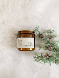 a candle sitting on top of a white fur covered floor next to some pine cones