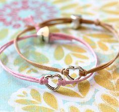 two bracelets with hearts on them sitting on top of a flowered tablecloth