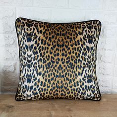 a leopard print pillow sitting on top of a wooden table next to a white brick wall