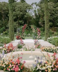 an outdoor ceremony setup with flowers and greenery on the ground, surrounded by tall trees