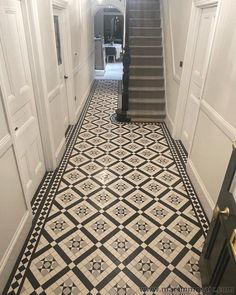 a hallway with black and white tile flooring next to a stair case in a house