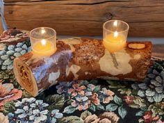 two candles are placed on a piece of wood that has been turned into a log