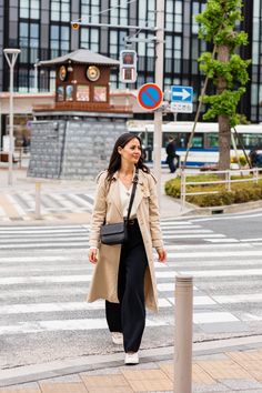 a woman walking across a cross walk in front of a tall building with lots of windows