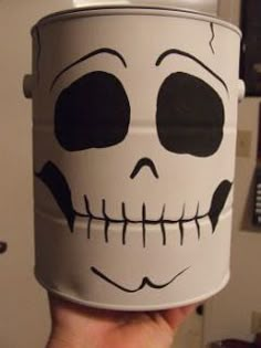 a hand holding a white cup with a skull painted on it