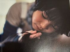 a woman is leaning against a wall with her hand on her chin and eyes closed