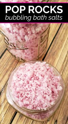 two jars filled with pink bath salts on top of a wooden table