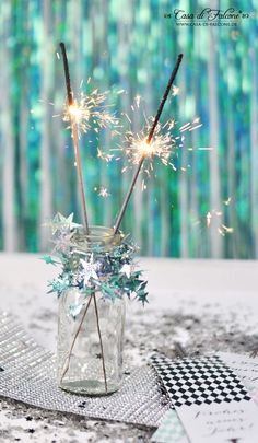 two sparklers are in a glass jar on a table