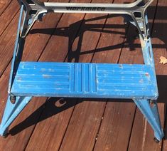 a blue bench sitting on top of a wooden floor next to a metal frame with wheels