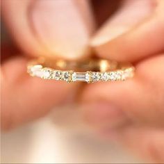 a close up of a person's hand holding a wedding ring with three stones