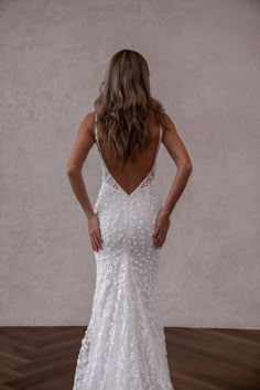 a woman in a white wedding dress standing with her back to the camera