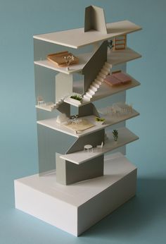 a model of a house with stairs and furniture on it's sides, against a blue background