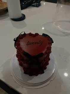 a heart shaped cake sitting on top of a white counter next to a glass vase