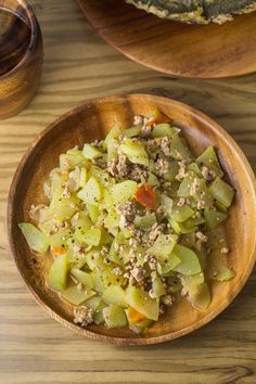 a wooden bowl filled with food sitting on top of a table next to another bowl