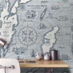 a desk with a chair, lamp and map wallpaper on the wall behind it