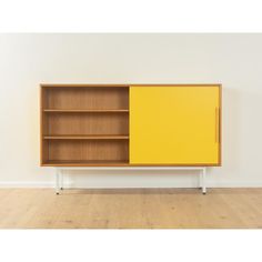 a yellow cabinet sitting on top of a hard wood floor next to a white wall