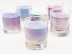 several different colored candles sitting in glass cups