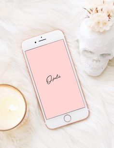 an iphone sitting on top of a white fur covered floor next to a vase with flowers