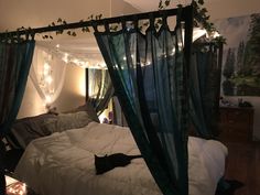 a canopy bed with curtains and lights hanging from it's sides in a bedroom