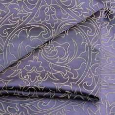 a purple and gold paisley print fabric with silver thread on the bottom, it is very soft