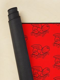 a black yoga mat with red cartoon images on it next to an empty yoga mat