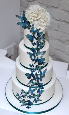 a wedding cake decorated with blue butterflies and flowers