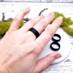 a person's hand with two black rings in front of them on a white surface