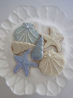 decorated cookies on a plate with shells and seashells in the middle, along with starfish