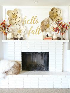 a fireplace decorated with paper flowers and gold foil lettering that says hello fall on the mantle