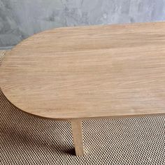 a wooden table sitting on top of a carpeted floor next to a gray wall