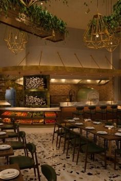 an empty restaurant with tables, chairs and plants hanging from the ceiling over it's dining area