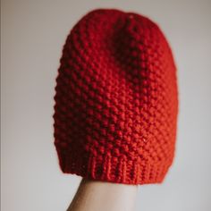 a hand wearing a red knitted hat