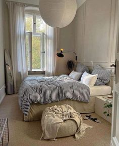 a bed room with a large bed and a lamp hanging from the ceiling next to a window