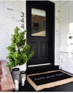 a black front door with a welcome mat and potted plant