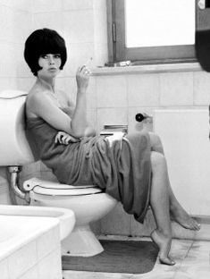 a woman sitting on top of a toilet in a bathroom