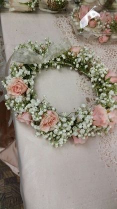 a table topped with a white and pink flower wreath on top of a cloth covered table