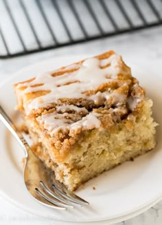 a slice of cinnamon roll cake on a plate with a fork and cooling rack in the background