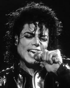 michael jackson singing into a microphone with his hair in the air and wearing black leather jacket