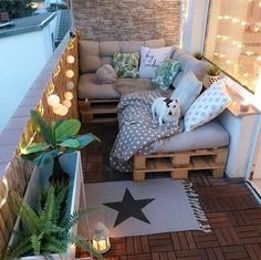 a small patio with a couch, table and potted plants