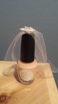 a bottle of nail polish sitting on top of a wooden table next to a veil