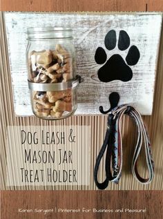 a mason jar filled with dog treats next to a leash holder on a wooden wall